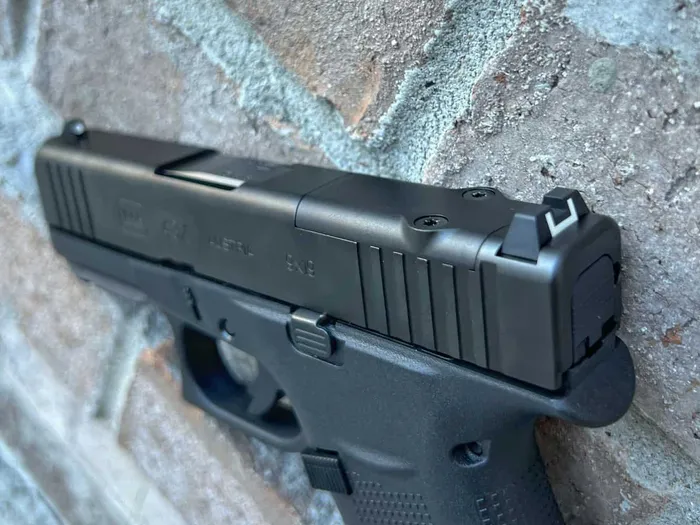 a close up of a Glock 43x on a brick wall
