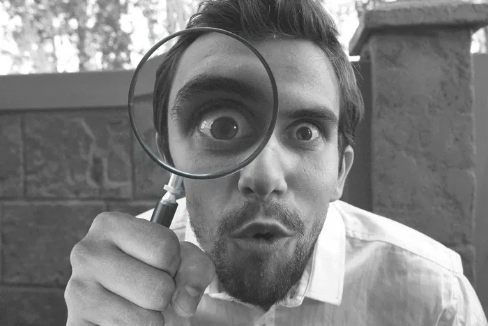 man looking through magnifying glass black white